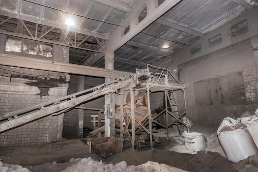 Old conveyor belt in the industrial workshop of the plant or enterprise for the processing of sand, soil and land factory.