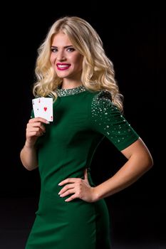 blonde woman in posing with cards for gambling on black background