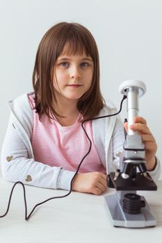 Child girl in science class using digital microscope. Technologies, children and learning.