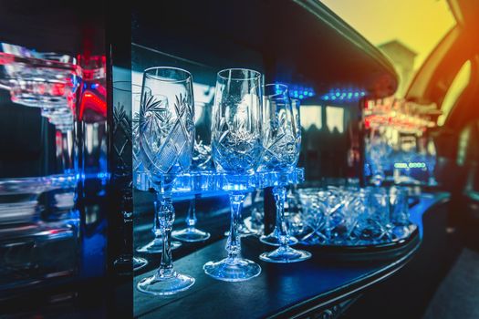 Glass glasses in neon lighting inside the luxury car limousine.