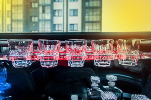 Glass glasses in neon lighting inside the luxury car limousine.