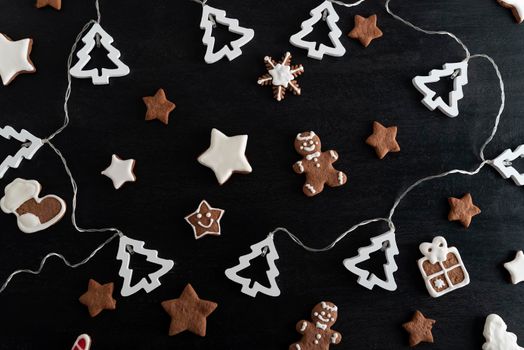 Christmas glazed painted cookies on black background top view.