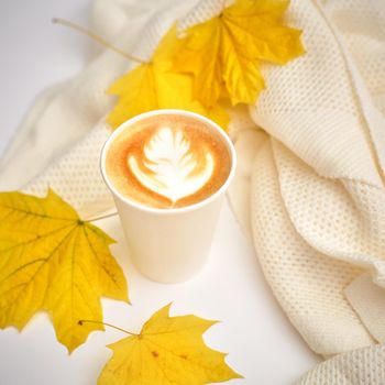 Paper coffee cup on autumn fall leaves with latte art. Street coffee, top view. selective focus