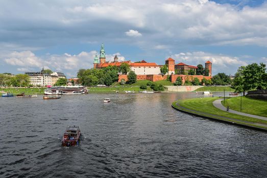 Krakow, Poland - May 20, 2019: Spring view on Wawel Castle, Vistula River, spring park, bicycle lane and walking tourists