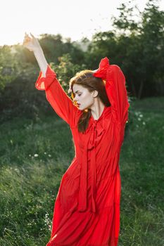 attractive woman in red dress posing in nature green grass. High quality photo