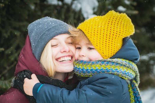 Young mother with cute child at winter snowy park. Winter family holidays. Close up portrait