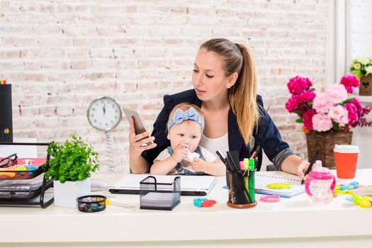 Family Business - telecommute Businesswoman and mother with kid is making a phone call. At the workplace, together with a small child