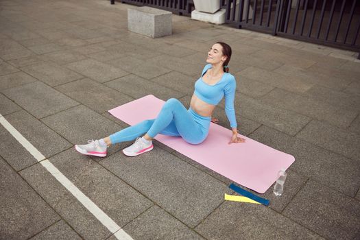 Beautiful fit caucasian woman is doing exercises outdoors at the city