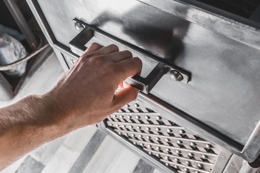 A male hand opens the handle of an iron cabinet or drawer.