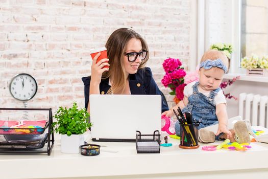 Businesswoman mother woman with a daughter working at the computer. At the workplace, together with a small child