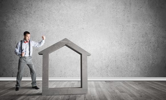 Determined businessman going to break with fist house concrete figure