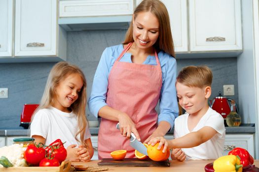 Young mother cooking with her children in kitchen