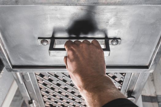 A men's hand opens the handle of an iron cabinet or drawer.
