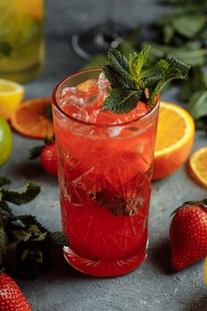 Colorful refreshing drinks for summer, cold strawberry lemonade juice with ice cubes in the glasses garnished with sliced fresh lemons.