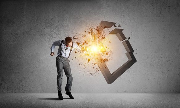 Determined businessman jumping and breaking with fist house concrete figure