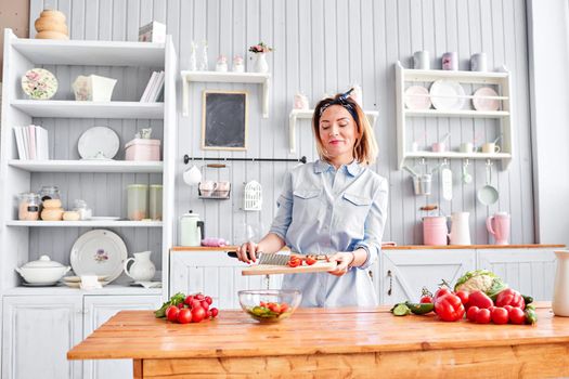 Beautiful young woman is preparing vegetable salad in the kitchen. Healthy Food. Cooking at home. Dieting Concept