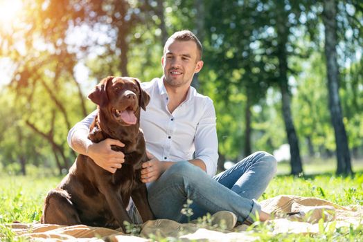 Young man hugs a dog. Spending time with friends in the park