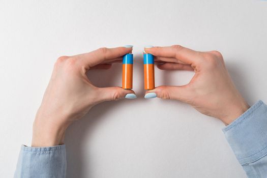 woman hands holding two AA batteries on white background. Generic accumulator.
