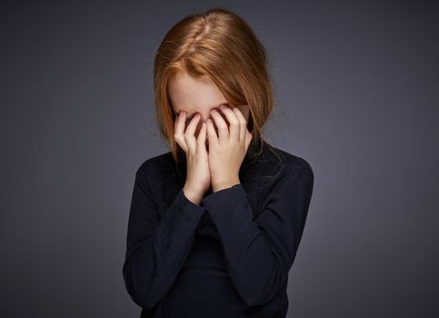 red-haired girl with freckles on her face in a black sweater posing. High quality photo