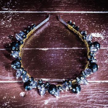 The headband with stones lies on a wooden old table. Photographed in light brush technique- image