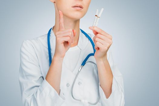 Unrecognizable doctor holds broken cigarettes, smoking cessation