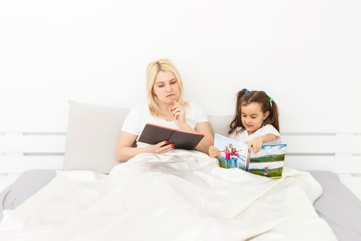 mother and daughter in bed watching a photo book