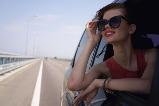 a woman is driving in a car on the road and looking out of the window. High quality photo