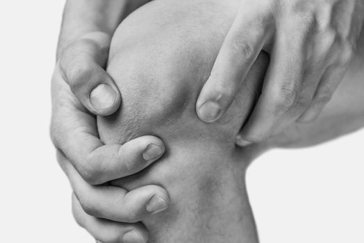 The man is touching the knee joint due to acute pain. Monochrome image, isolated on a white background