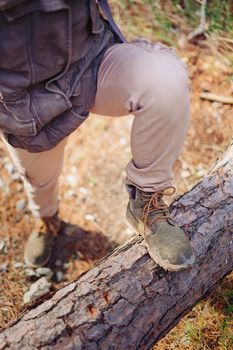 Woman hiker standing on tree trunk in the forest outdoor. View of legs. Hiking and leisure theme