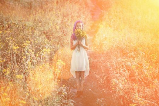 Young woman with blue hair and a bouquet of flowers standing in a field. Image with sunlight effect
