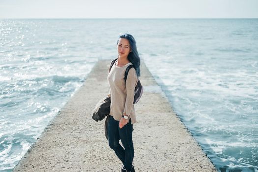 Young woman standing on a pier on background of sea