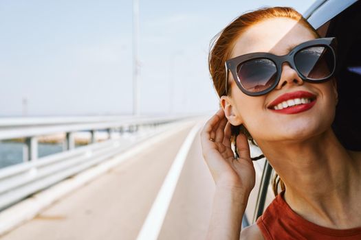 cheerful woman peeking out of the car window trip adventure lifestyle. High quality photo