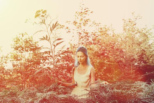 Beautiful girl with blue hair walking in fairy forest, girl standing near a big flower. Image with sunlight effect