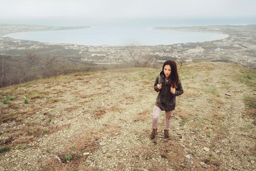 Hiker young woman with backpack walking up on mountain over the bay outdoor