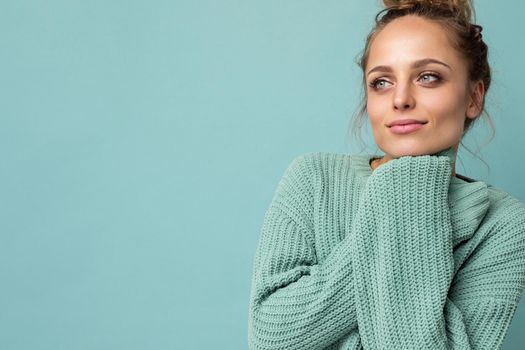 Portrait of young beautiful smiling hipster woman in trendy outfit. Sexy carefree female person posing isolated near blue wall in studio with free space. Positive model with natural makeup.