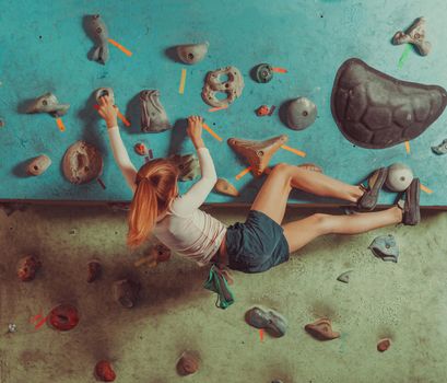 Little girl climbing on artificial boulders in gym