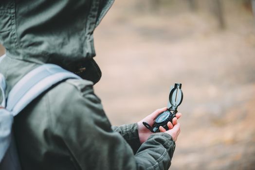 Hiker young woman searching direction with a compass in the forest, close-up