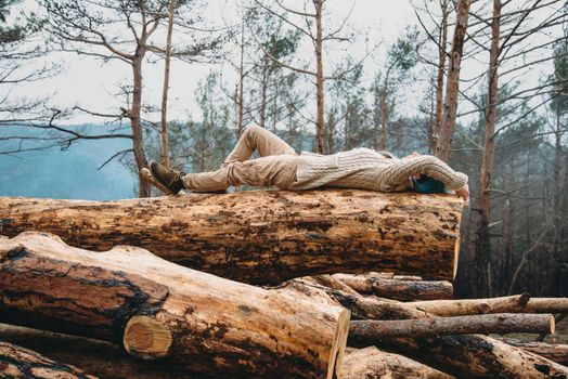 Beautiful young woman with blue hair lying on fallen tree trunk. Girl resting outdoor