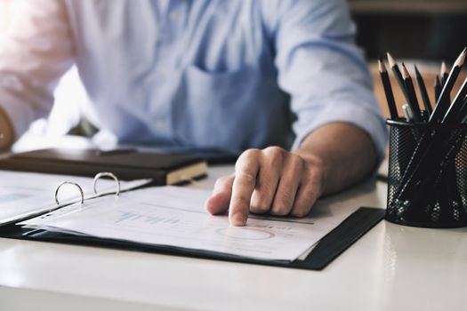 Examining the financial budget, a male auditor is pointing to a file to summarize the company's irregular financial budget