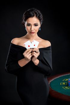 sexy woman with poker cards. Female player in a beautiful black dress. girl stands near the poker table and holds two aces