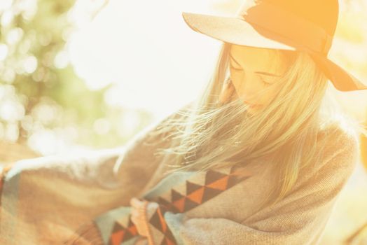 Attractive fashionable girl in a hat and poncho walking at sunny day outdoor