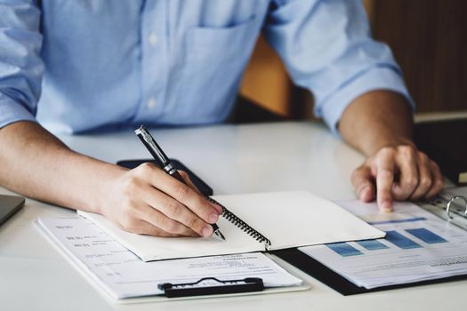 financial budget audit A male auditor is using a pen to write down budgets to trace the company's financial fraud