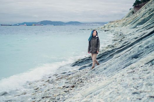 Beautiful girl walking on coast near the sea and stone rocks outdoor