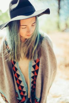 Beautiful young woman in a hat and poncho outdoor