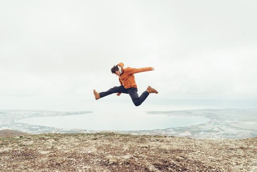 Happy young man jumping on peak of mountain above the sea bay