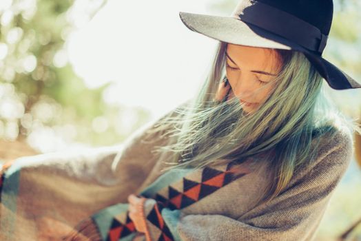 Attractive fashionable girl in a hat and poncho walking outdoor