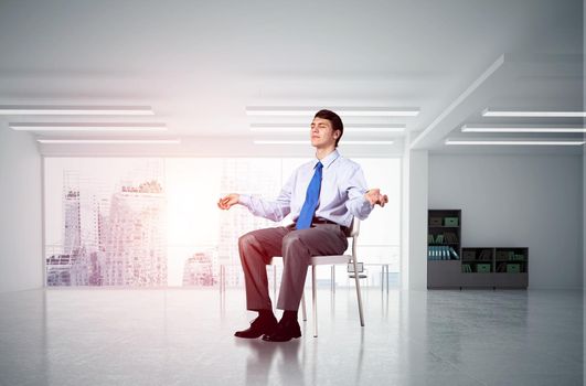 young businessman in the office meditates, achieve calmness, to achieve the goal