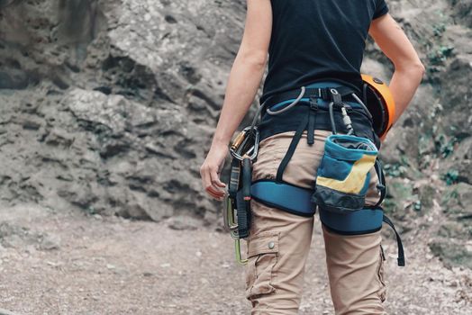 Unrecognizable woman rock climber wearing in safety harness with climbing equipment and helmet outdoor