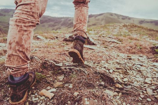 Hiker walking up on mountain in rainy weather. View of legs