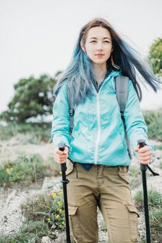 Beautiful hiker young woman with trekking poles walking in summer outdoor